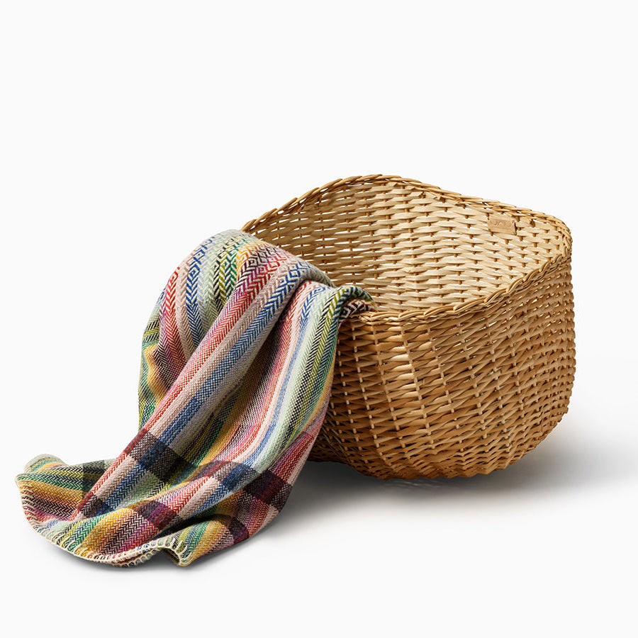 Wicker basket with a colorful striped towel on a white background