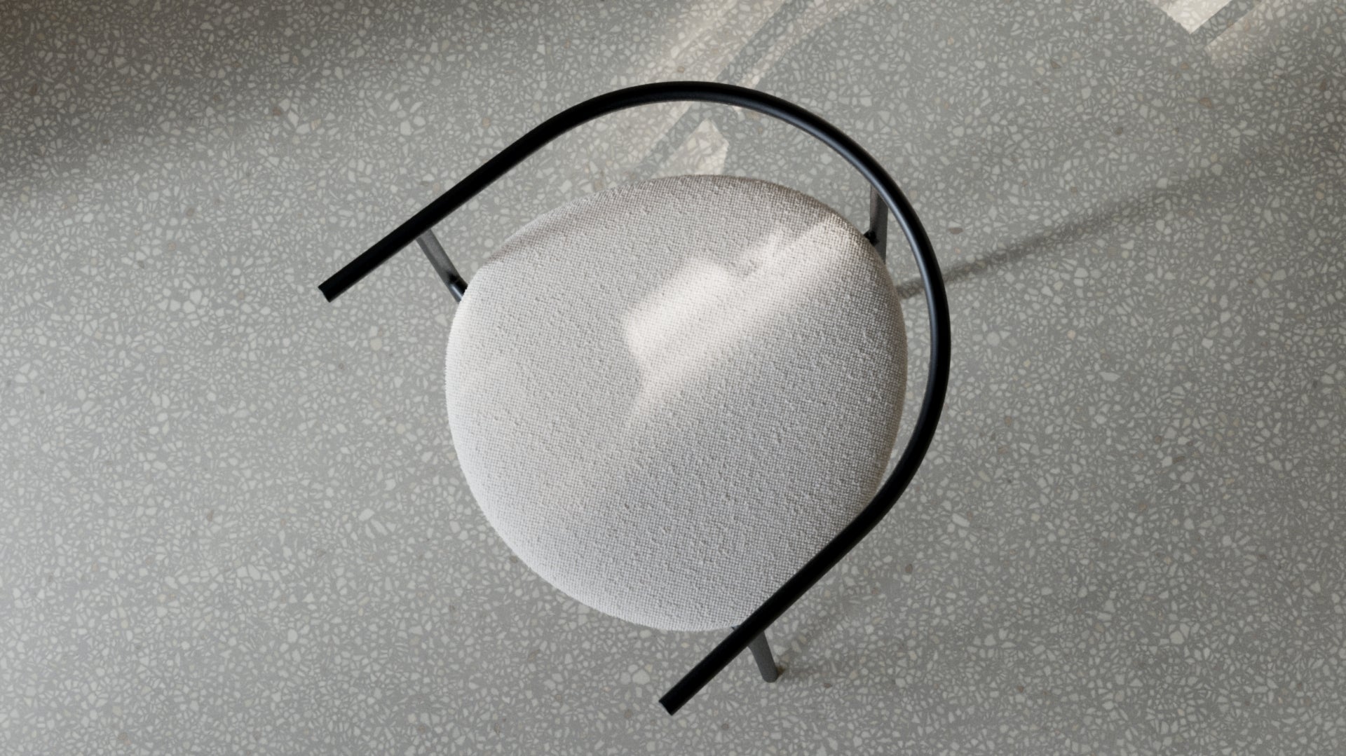 Close-up of a small, round chair with a black curved feature on a textured surface